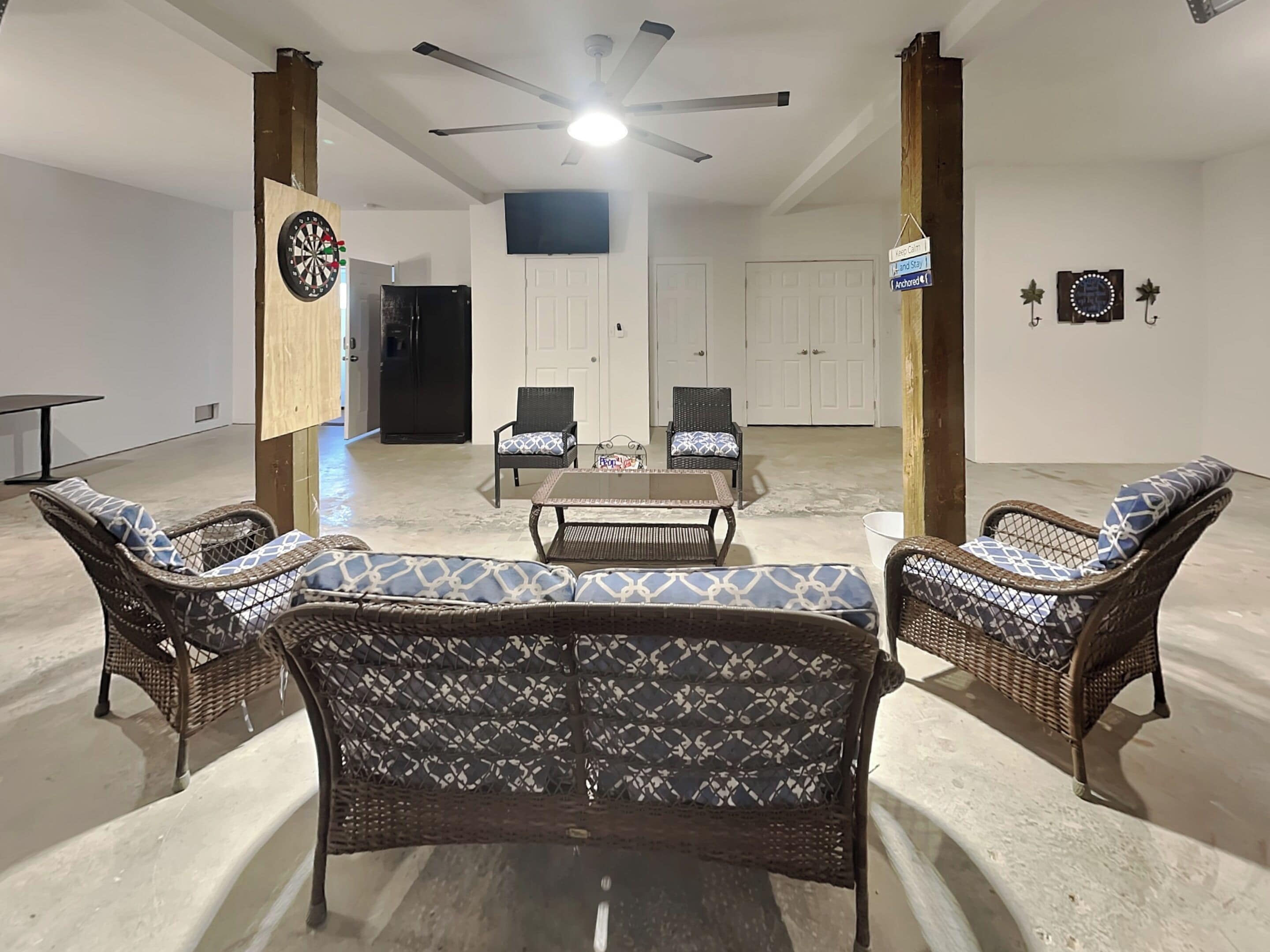 Sala de estar com móveis de vime, um alvo de dardos e um ventilador de teto.