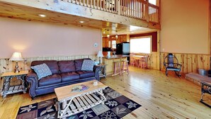 Un intérieur de cabine spacieux, avec un plancher en bois, un canapé, une table basse, un coin repas et une cuisine.