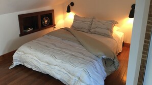 A bedroom with a bed, wooden flooring, a wall-mounted shelf with a fan, and two wall-mounted lamps. - Cozy studio with AC and WiFi in Historic Geneva, NY.  (Geneva)