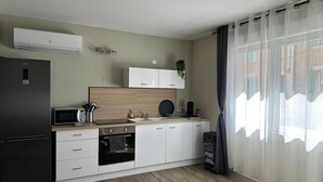 Una cocina moderna con refrigerador negro, microondas y horno, armarios blancos y un salpicadero de madera.