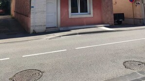 Un edificio de dos pisos con fachada rosa y detalles blancos, con dos ventanas en el nivel superior y una puerta en la planta baja.