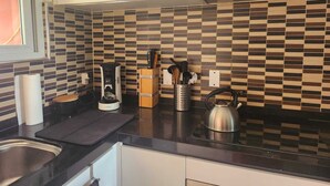 A kitchen with a checkered backsplash, a coffee maker, a kettle, and utensils on the counter. - Charming 2-bedroom resort apartement with AC, WiFi in beautiful Willemstad (Willemstad)