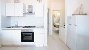 Una cocina moderna con armarios blancos, estufa a gas, horno y refrigerador.