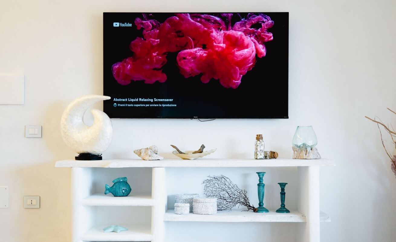 Et hvidt TV-møbel med et fladskærms-tv, der viser et pink abstrakt billede.