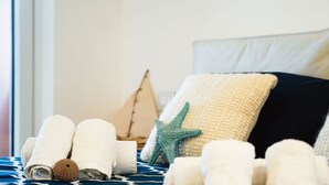 A neatly made bed with rolled towels, a starfish decoration, and a sailboat pillow. - Palau | Bella Vista Apartment | vista mare e terrazzo (Palau)