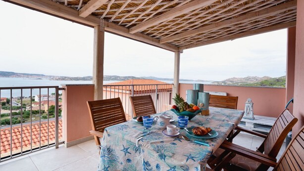 A balcony with a table set for two, overlooking a coastal view. - Palau | Bella Vista Apartment | vista mare e terrazzo (Palau)
