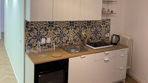 Une cuisine moderne avec des armoires blanches, un pare-feu décoré, un plan de travail en bois et un luminaire suspendu.