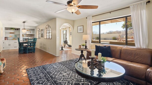 A spacious living area with a ceiling fan, a glass coffee table, a leather sofa, and a view of the outdoors. - Spacious Tubac Escape – 4BR/3BA, Private Pool, Bar, Workout Room & 2 King Suites (Tubac)