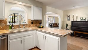 A kitchen with white cabinets, a large island, and a piano in the background. - Spacious Tubac Escape – 4BR/3BA, Private Pool, Bar, Workout Room & 2 King Suites (Tubac)