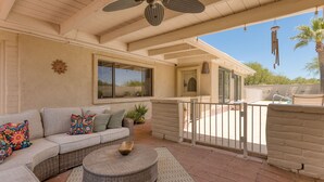 A covered patio area with a wicker sofa, a round table, and a ceiling fan. - Spacious Tubac Escape – 4BR/3BA, Private Pool, Bar, Workout Room & 2 King Suites (Tubac)