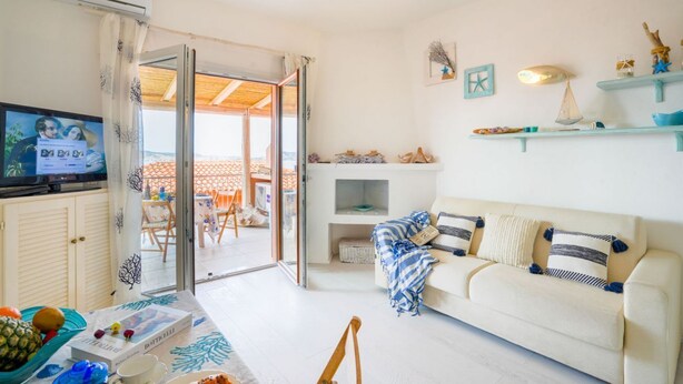 Un salón con sofá, televisión y vistas al exterior.
