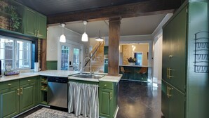 A kitchen with green cabinets, a central island, and a staircase leading to another level. - Stillwater's Enchanted Escape (Stillwater)