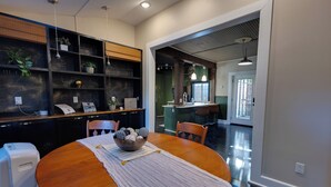 A dining area with a wooden table, chairs, a bowl of fruit, and a buffet counter with shelves and plants. - Stillwater's Enchanted Escape (Stillwater)