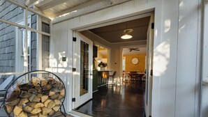 A covered outdoor area with a firewood stack, a dining area with chairs and a table, and a ceiling fan. - Stillwater's Enchanted Escape (Stillwater)