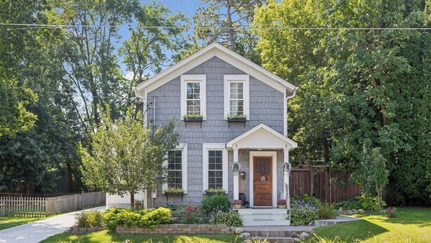 A two-story house with a front porch, a wooden door, and a mailbox. - Stillwater's Enchanted Escape (Stillwater)