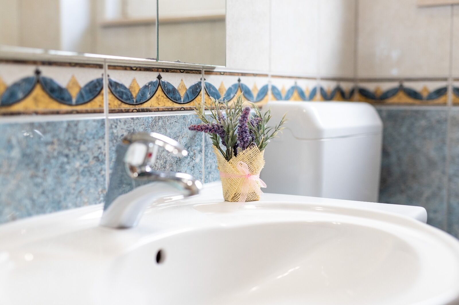 A bathroom sink with a decorative vase of flowers and a modern faucet.