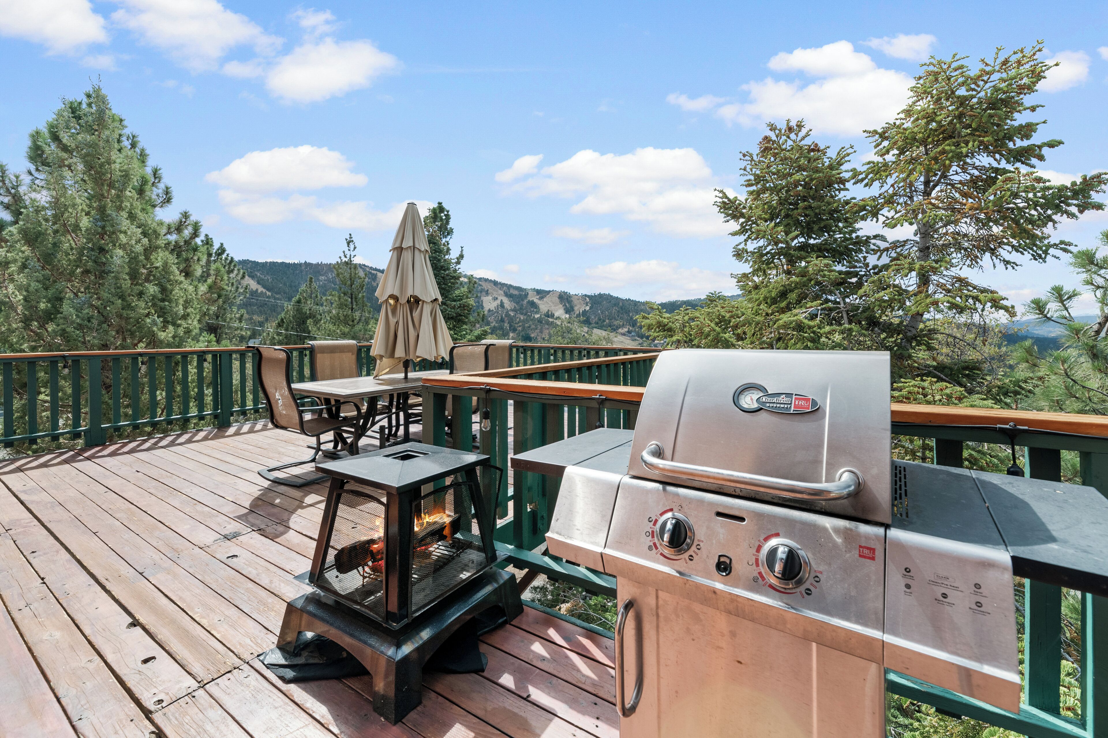 A wooden deck with a grill and a table with an umbrella.