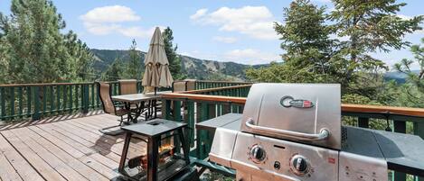 A wooden deck with a grill and a table with an umbrella.