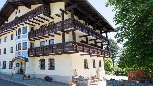 A traditional building with a balcony, a sign reading "Gasthof zur Alten Post," and a paved entrance area with outdoor seating. - Gasthof zur alten Post (Regen)