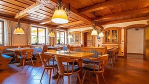 Un restaurant amb taules i caires de fusta, llums penjants i grans finestres.