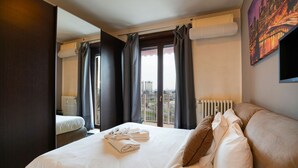 Ett hotellrum med en stor säng, utsikt över staden genom fönstret och en tavla på väggen.