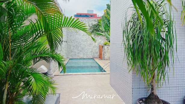 Una zona de piscina con un muro de piedra y plantas en macetas.