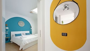 A modern bedroom with a bed, a circular mirror, and a blue accent wall.