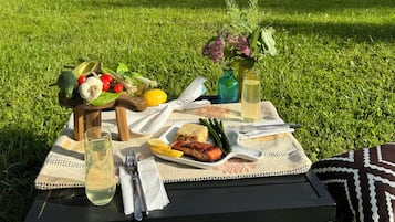 Un pique-nique est installé sur un champ herbeux, avec une table, de la nourriture et des boissons.