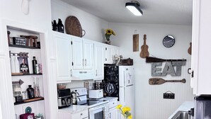 Een moderne keuken met witte kasten, een centraal eiland en een rustieke houten accentmuur.