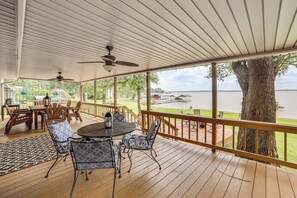 A covered outdoor deck with a table and chairs, overlooking a body of water. - Waterfront Retreat w/ Dock on Cedar Creek Lake! (Kemp)