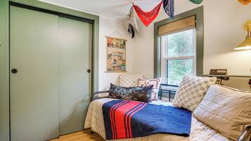 A bedroom with a bed, pillows, a blanket, a window, and a door.