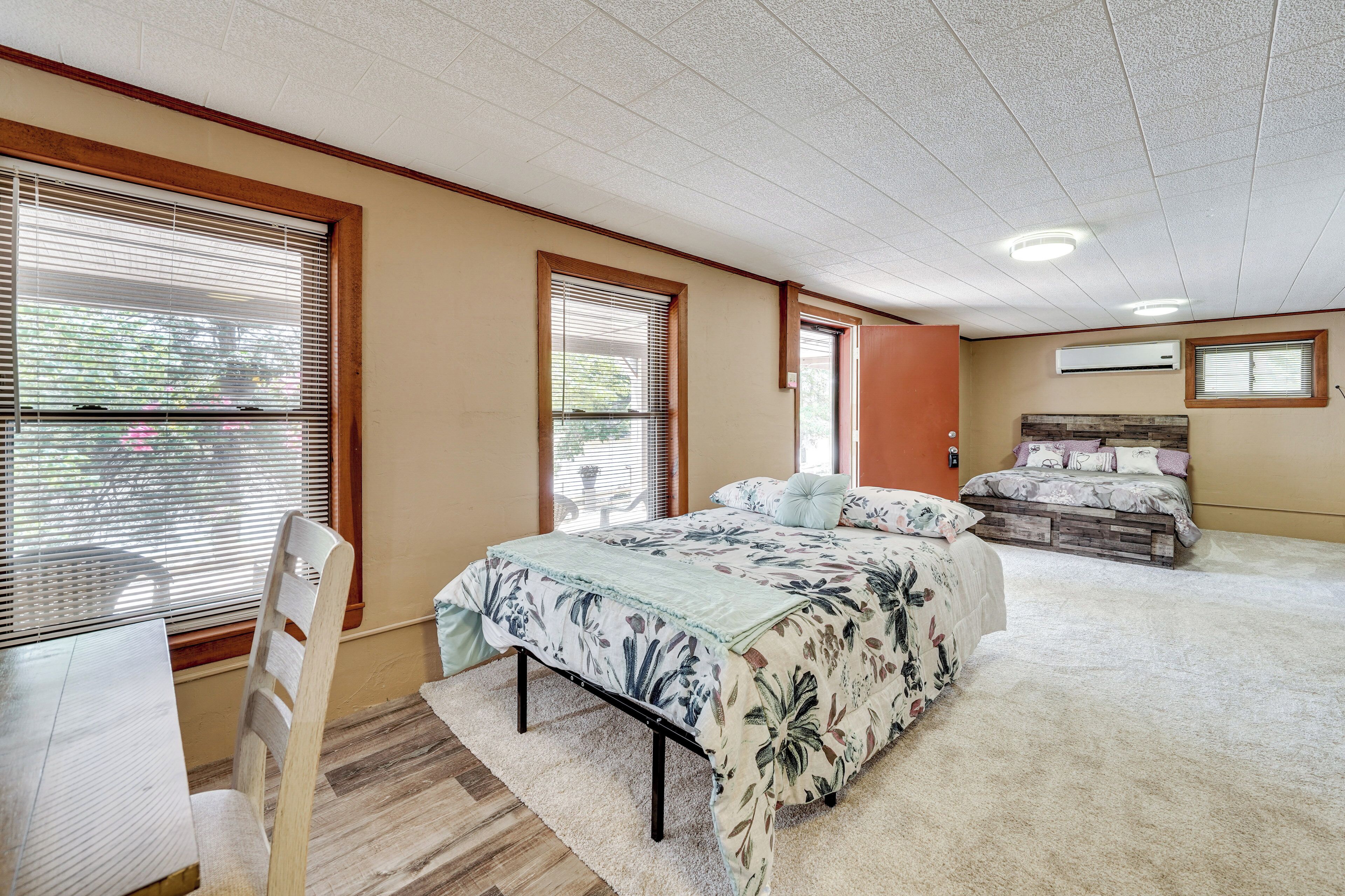 A bedroom with a bed, a chair, a desk, and a window with blinds.