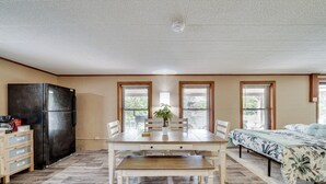 A spacious kitchen with a dining table, chairs, a bench, a refrigerator, and a potted plant. - Waterfront Retreat on Raymond Gary State Lake (Fort Towson)