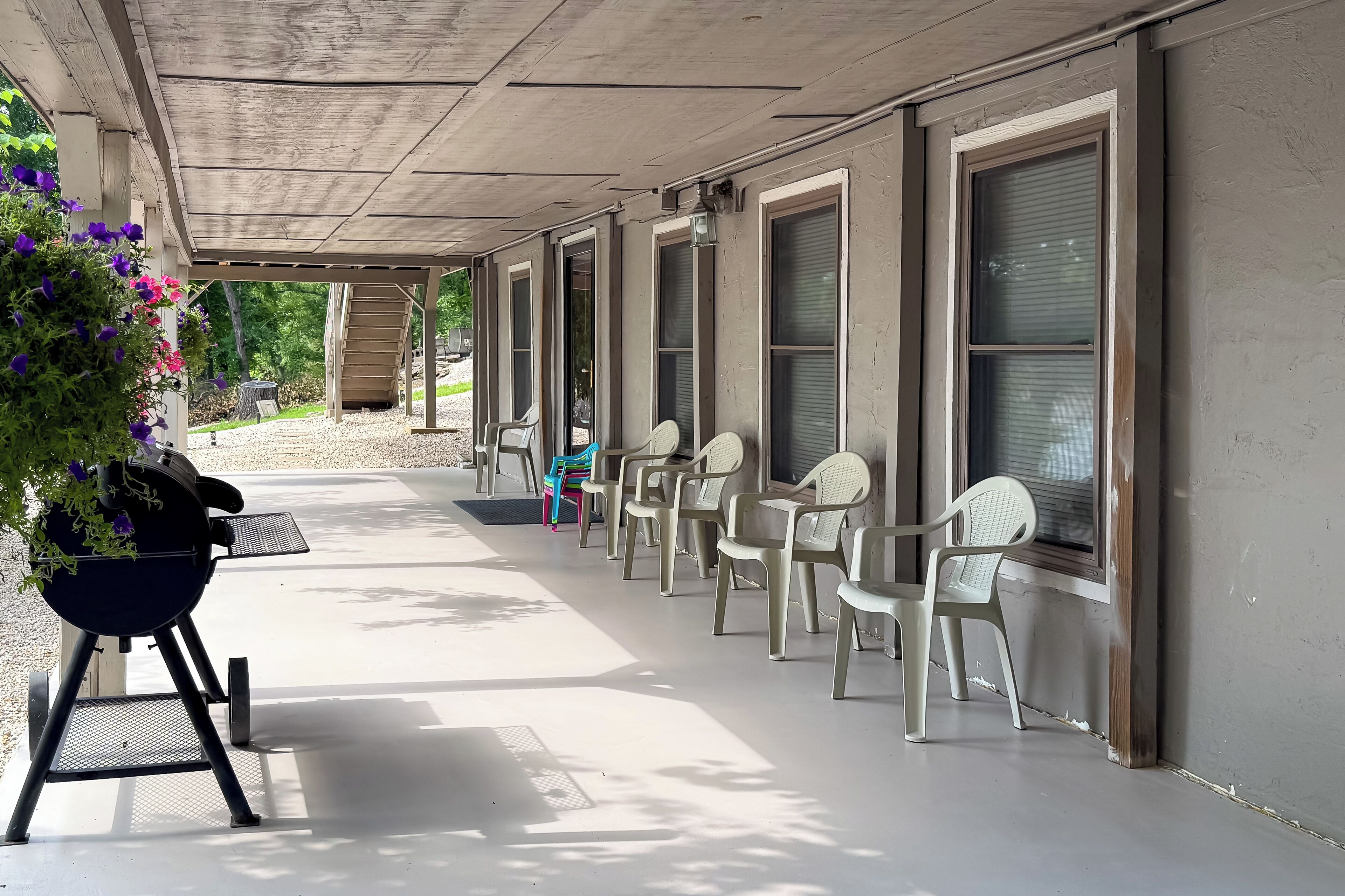Un espace extérieur abrité avec des chaises en plastique et un barbecue.