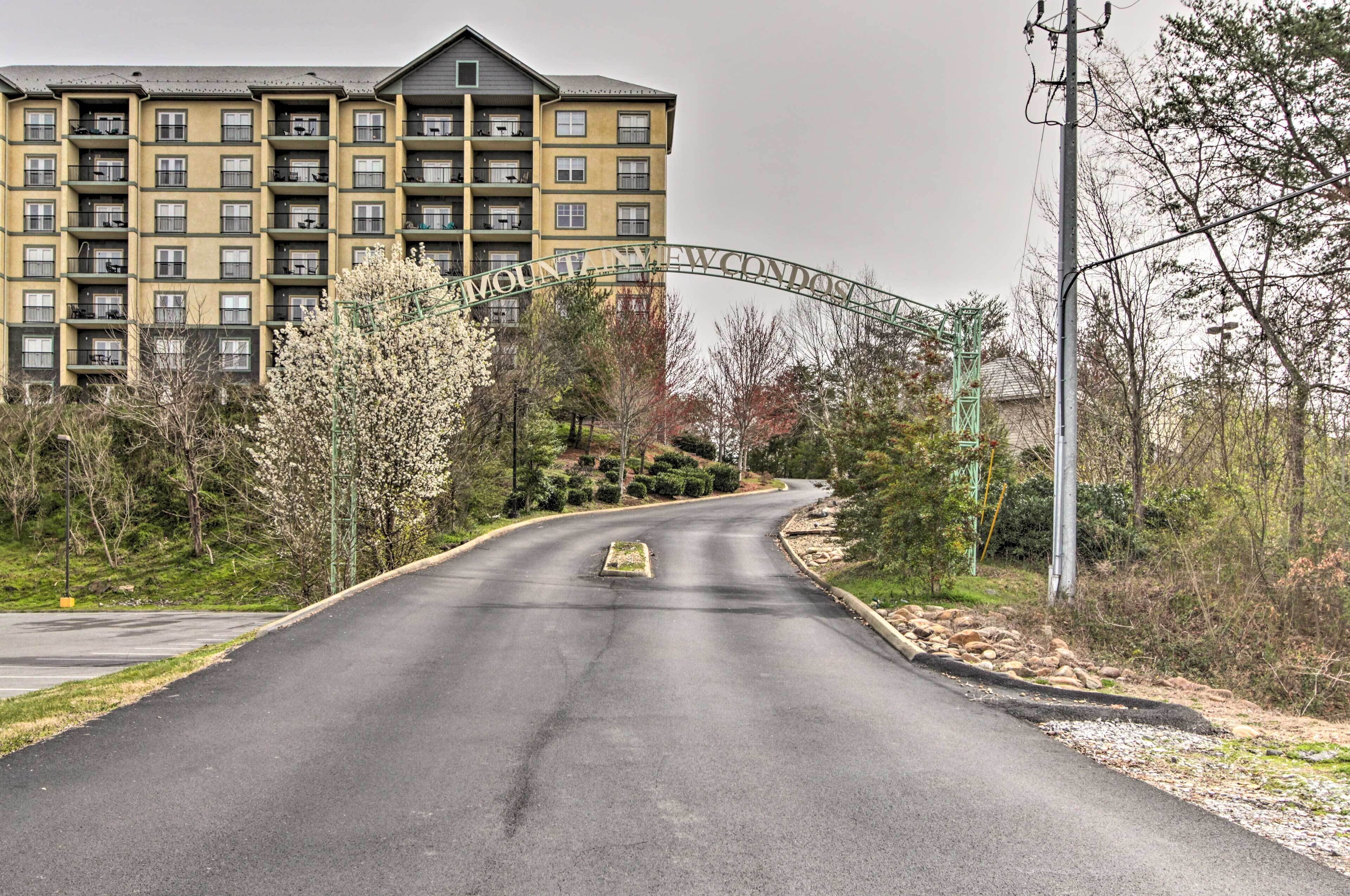 A multi-story building with a large entrance archway, surrounded by trees and a paved road.