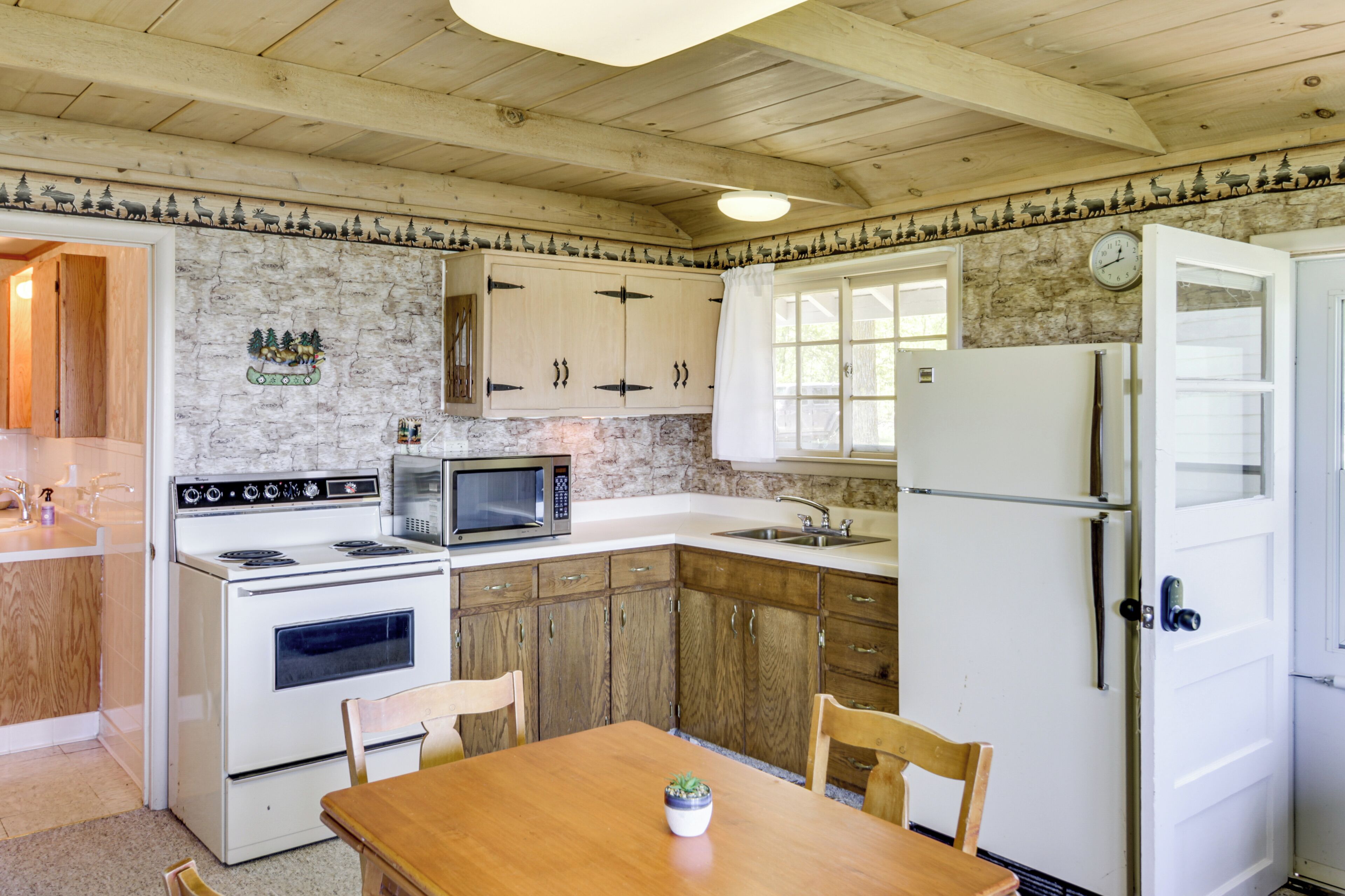 A kitchen with wooden cabinets, a microwave, a refrigerator, and a dining table with chairs.