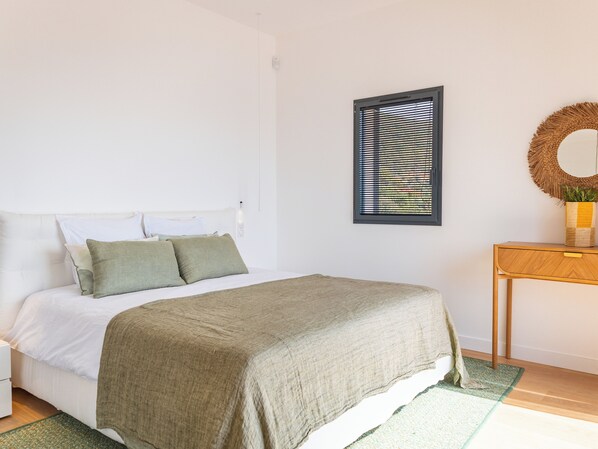 A neatly arranged bedroom with a bed, bedside table, and a wall-mounted mirror.