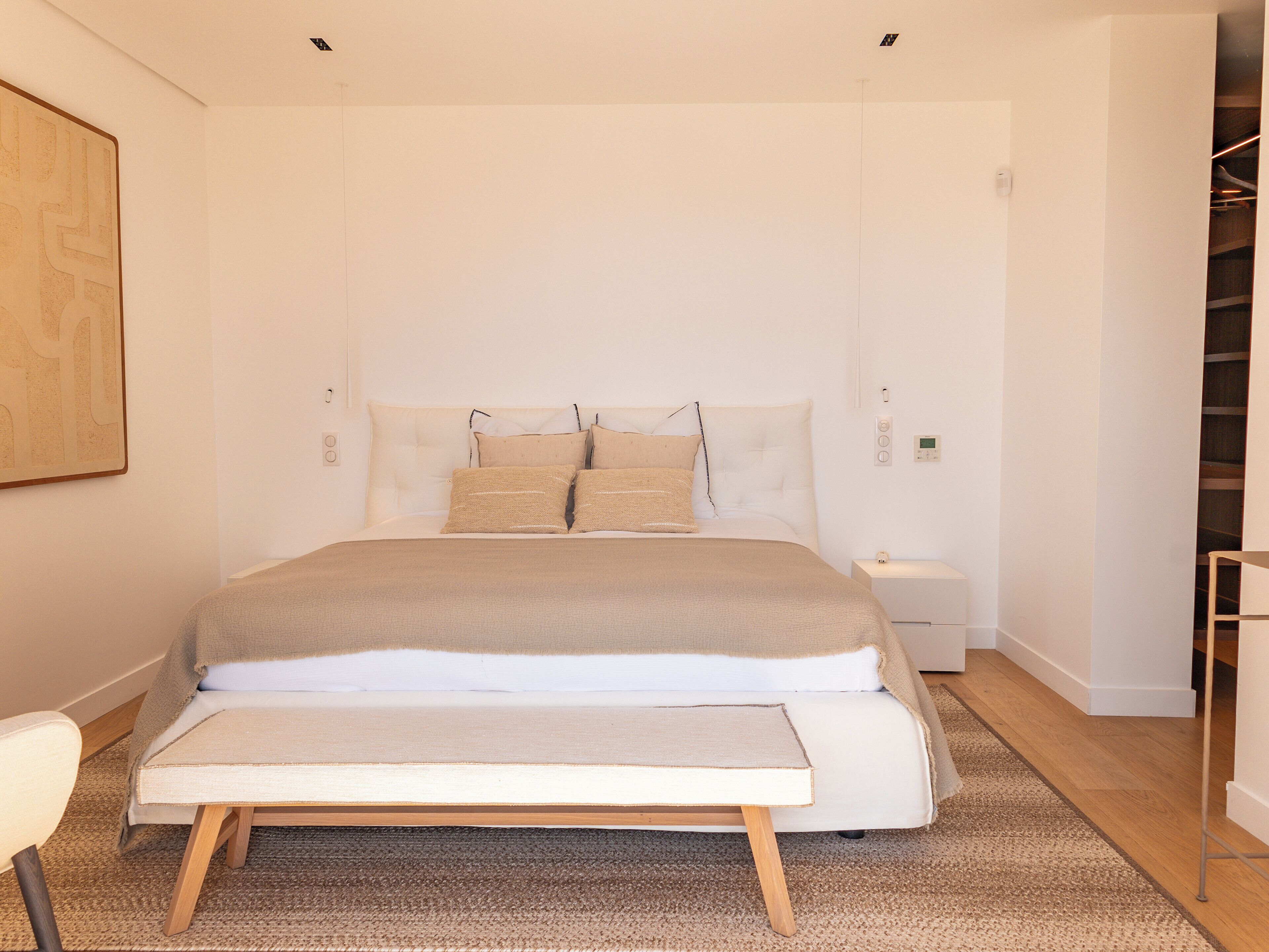 A modern bedroom with a large bed, a bedside table, and a chair.