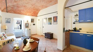 Una sala de estar acogedora con chimenea, una mesa de comedor para cuatro comensales y una cocina con alacenas azules.