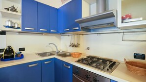 Una cocina moderna con armarios azules, un lavamanos de acero inoxidable, una estufa a gas y un lavavajillas.