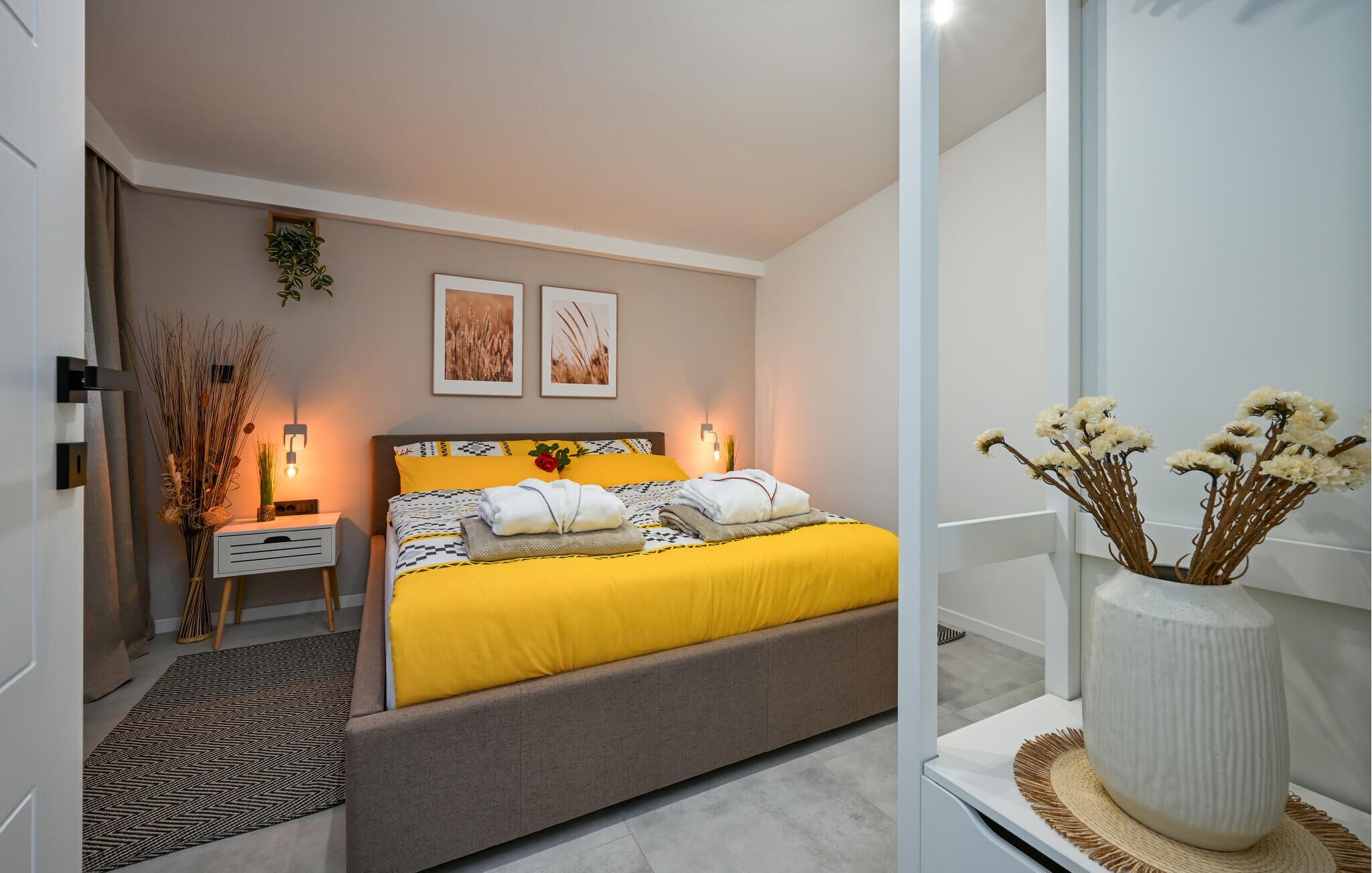 A modern bedroom with a large bed, bedside tables, and decorative wall art.