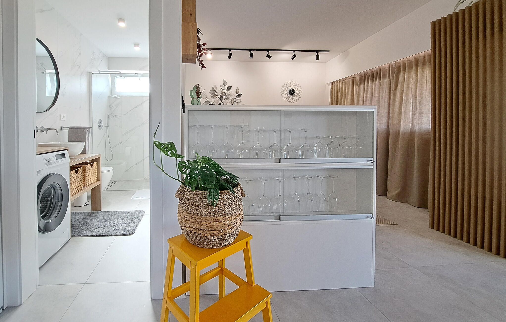 Une salle de bain moderne équipée d’un lave-linge, d’un évier et d’un miroir.