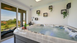 Een moderne spa ruimte met een bubbelbad, grote ramen en uitzicht op het platteland.