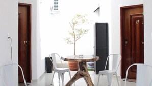 Ein modernes Zimmer mit rundem Tisch, weißen Stühlen, einem Holztisch und einem großen Fenster mit Blick auf einen Baum und ein Gebäude.