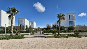 A modern building complex with a central pathway, palm trees, and a clear blue sky. - Beautiful home in Turanj (Turanj)