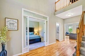 A bedroom with a bed, a nightstand, and a window. There is a staircase leading to an upper level. - Lakefront Lake Anna, Dock, Views, Deck, Movies (Mineral)