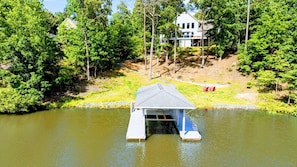 A house with a dock extending into a pond, surrounded by trees and a grassy area. - Lakefront Lake Anna, Dock, Views, Deck, Movies (Mineral)