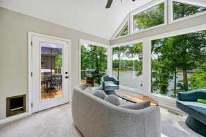 A modern interior with a large window, a gray sofa, and a view of a lake. - Lakefront Lake Anna, Dock, Views, Deck, Movies (Mineral)