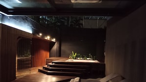 Un interior moderno con un escenario, una zona de asientos y un pequeño jardín.
