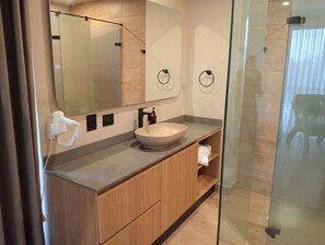 A modern bathroom with a large mirror, a wooden vanity, a white sink, and a glass shower enclosure. - Hotel Rulay Medellin (Medellín)
